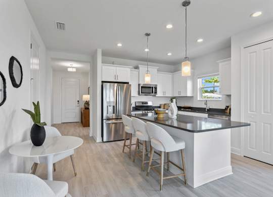 A modern kitchen with a white island and bar stools at Marisol in Lakewood Ranch, FL
