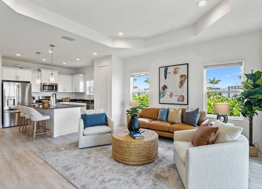 A modern living room with a white sofa, a grey rug, and a kitchen in the background at Marisol in Lakewood Ranch, FL