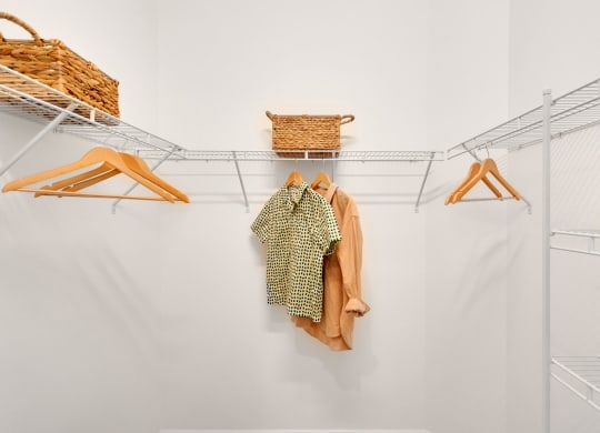 a walk in closet with a white wall and a closet organizer with clothes and baskets at Marisol, Bradenton, FL 34211
