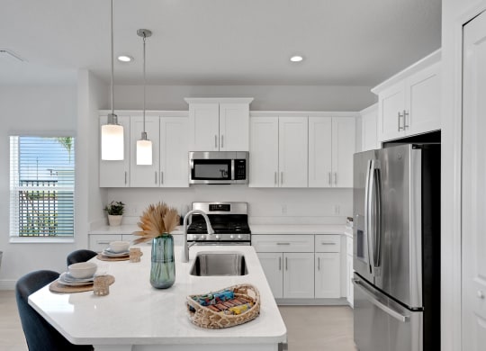 a white kitchen with stainless steel appliances and white cabinets at Marisol, Bradenton