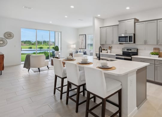 Open kitchen concept with stainless steel appliances, island with bar seating, and outdoor patio at Martinique Lakewood Ranch