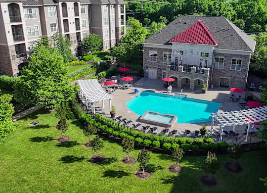 A large building with a red roof is surrounded by a pool and trees.