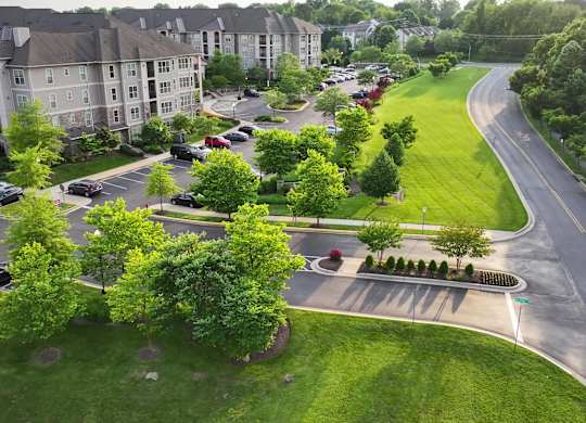 A road with a grassy median and apartment buildings on either side.