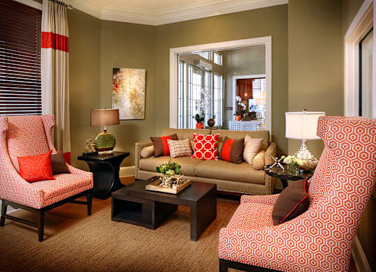 A living room with a red chair and a red and white patterned chair.