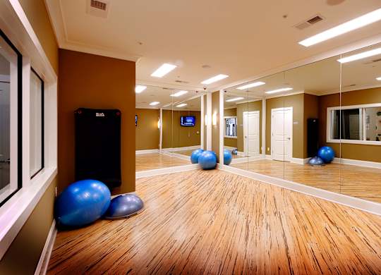 A gym with exercise balls and mirrors on the wall.