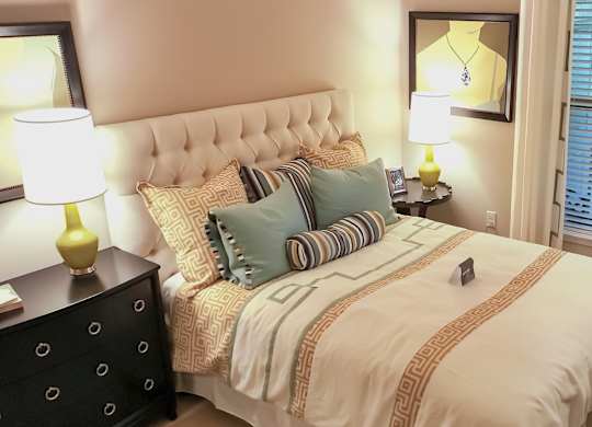 A bedroom with a bed, nightstand, and window with blinds.