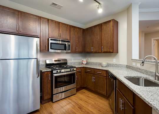 A kitchen with wooden cabinets and a stainless steel refrigerator.