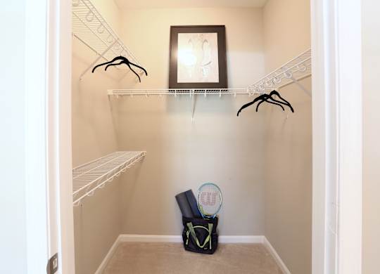 A small closet with a bag and a racket on the floor.