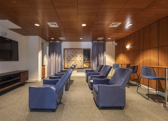 a large screening room with blue chairs and a television