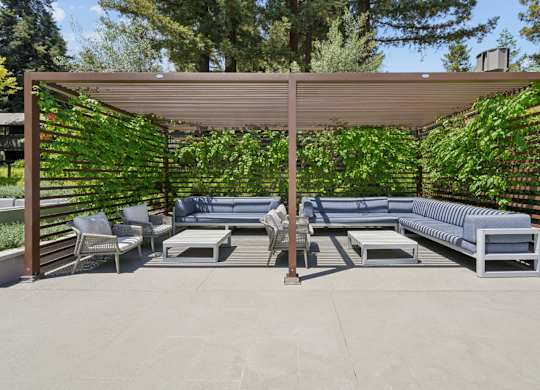 Covered outdoor cabana with seating and lounge furniture at Old Orchard Apartments