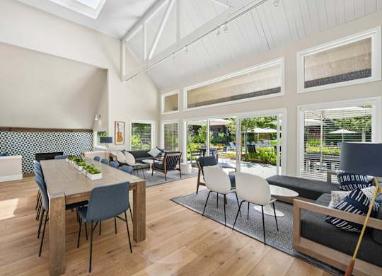 Clubhouse dining area with long wood table, blue accent mural wall, and adjacent kitchen
