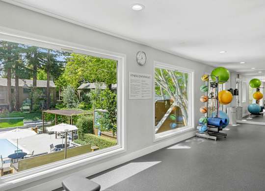 Fitness room with free weights, bench, and large window overlooking greenery at Old Orchard