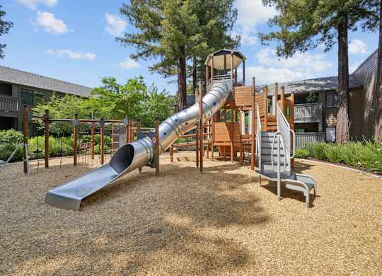 Community playground with slides and open space at Old Orchard Apartments