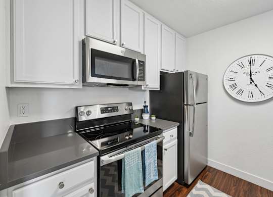 Modern kitchen at Old Orchard Apartments with stainless steel appliances and white cabinetry.