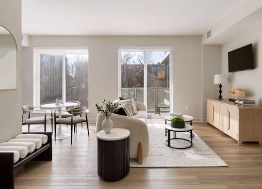 A modern living room with a white sofa, a white armchair, a white coffee table, and a white side table.