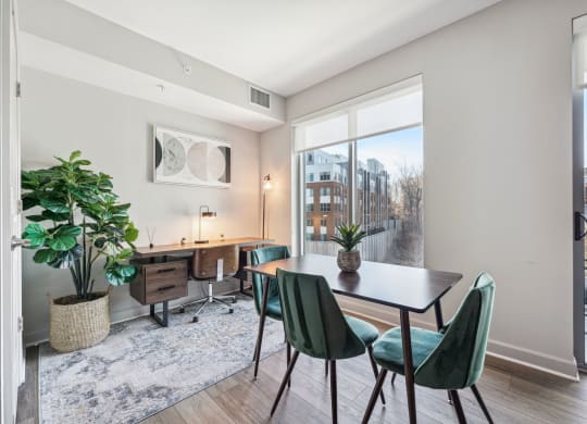 a dining room with a large window and a table with green chairs