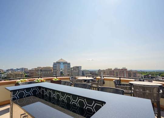 a rooftop patio with tables and chairs and a view of the city