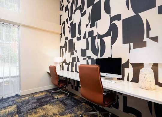 a room with two desks and two chairs and a window