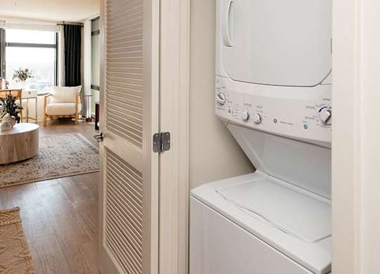 A white dryer is sitting in a room with a round table and chairs.