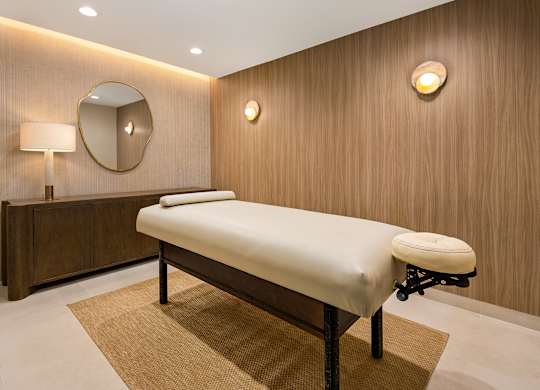 Private massage room with a padded treatment table, soft lighting, and neutral finishes in the Parc Huron spa.