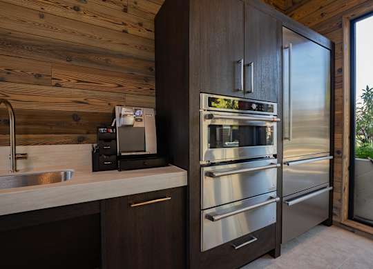 A modern kitchen with a wooden wall and stainless steel appliances.
