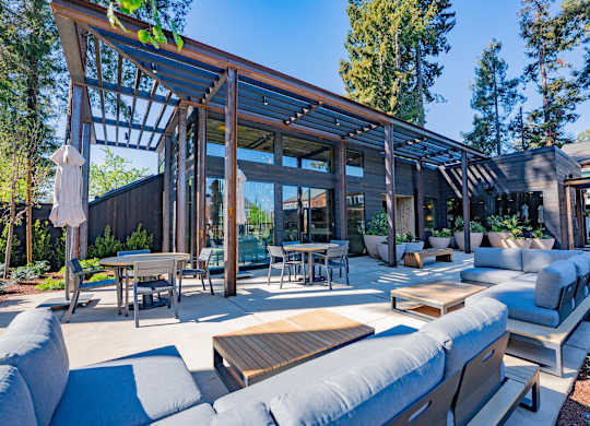 A modern outdoor living space with a wooden pergola and comfortable seating.