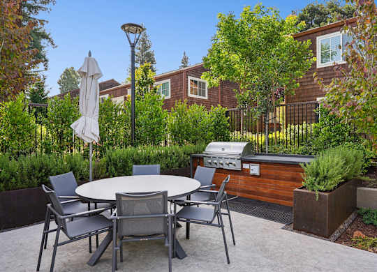 A patio with a table and chairs and a grill.