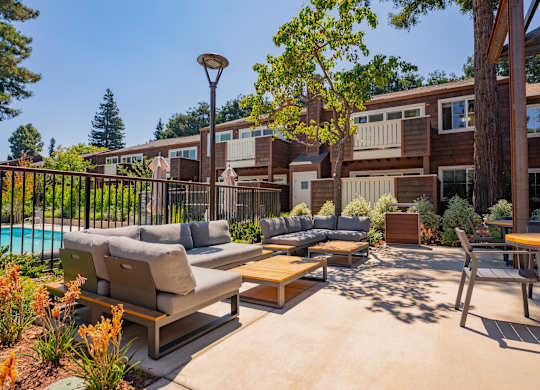 A sunny day at the poolside with a table and chairs.