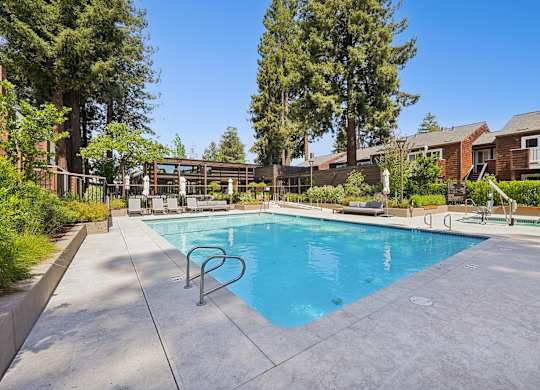 A swimming pool surrounded by trees and a building in the background.
