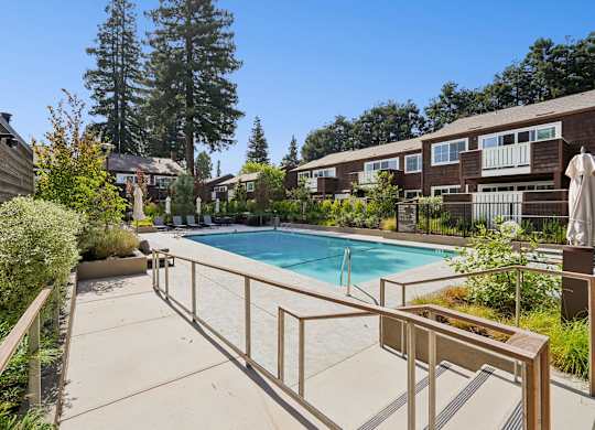 A pool surrounded by a fence and trees.