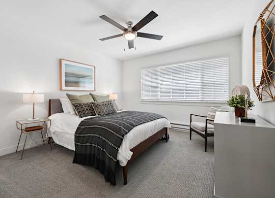 A bedroom with a bed, chair, and a ceiling fan.