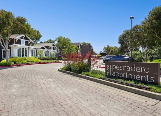Entrance sign and landscaped drive at Pescadero Apartments community.