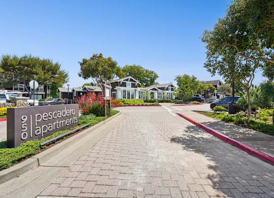 Entrance sign and landscaped drive at Pescadero Apartments community.