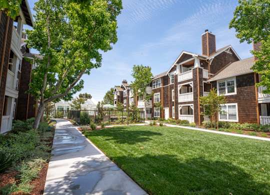 Landscaped courtyard at Pescadero Apartments with open lawn, walking paths, and garden-style surroundings.
