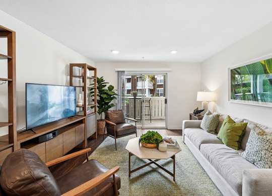 Apartment living room at Pescadero Apartments with modern seating, wood flooring, and private patio access.
