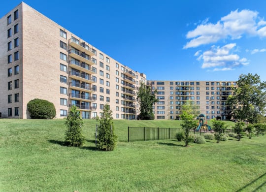 a large apartment building with a playground in a green park