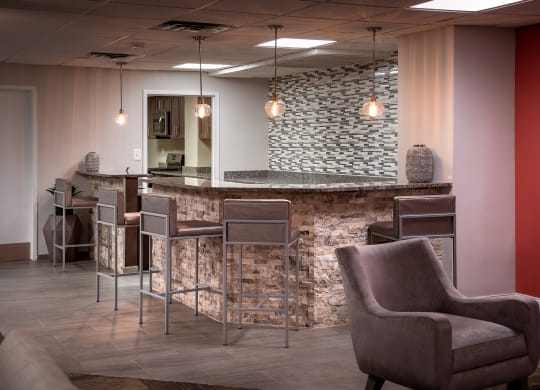 a lobby with chairs and a bar with a stone wall