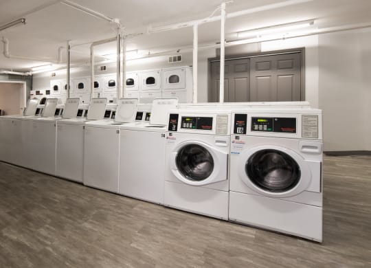a row of white washers and dryers in a laundry room
