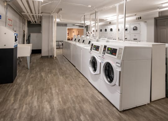 a row of white washers and dryers in a laundry room
