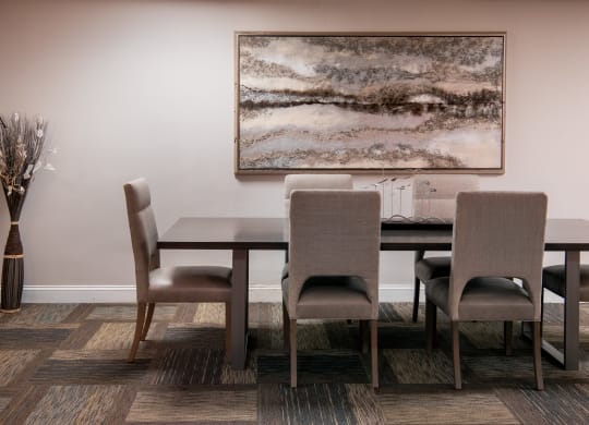 a dining room with a table and chairs and a painting on the wall