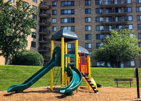 a playground with slides in front of an apartment building