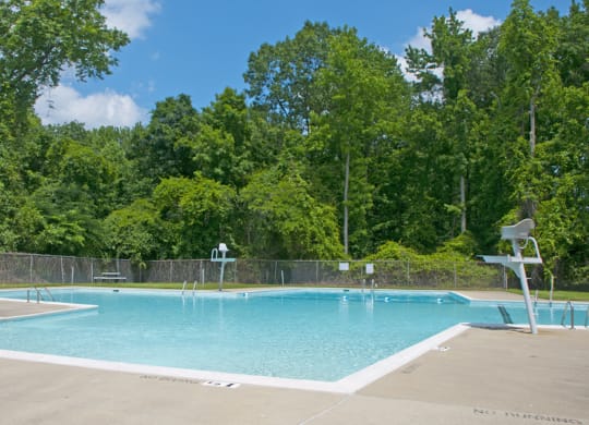 a swimming pool with a fence around it and trees in the background
