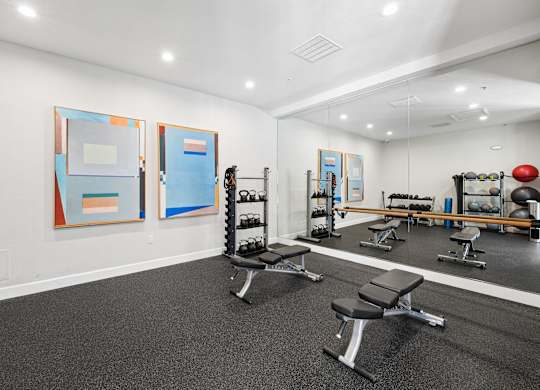 Fitness studio with mirrored wall, weights, and open floor space