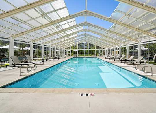Indoor pool with glass ceiling and lounge seating at The Presidio Apartments
