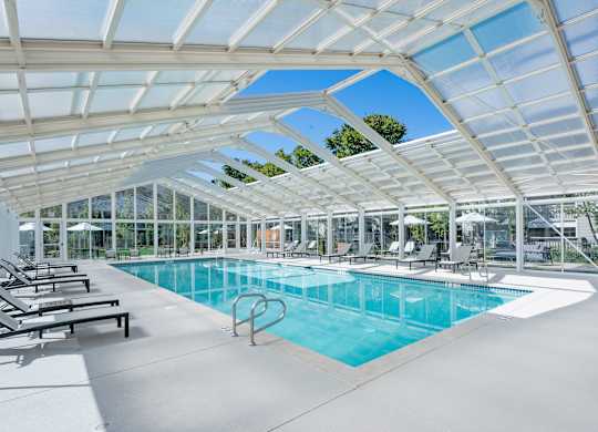Indoor pool with lounge chairs and glass enclosure