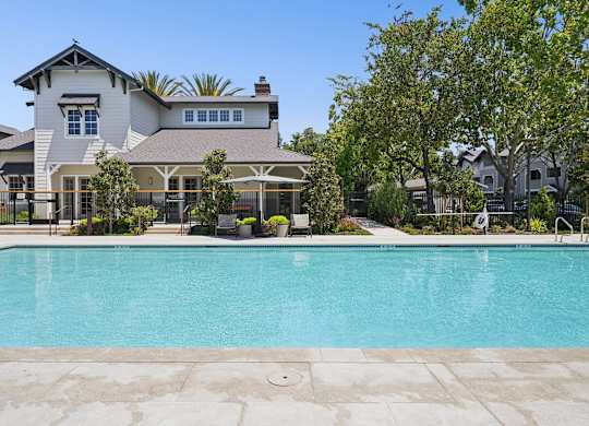 Outdoor pool with surrounding deck, seating, and landscaped areas