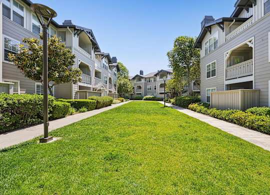 A row of apartment buildings with a green lawn in the foreground.