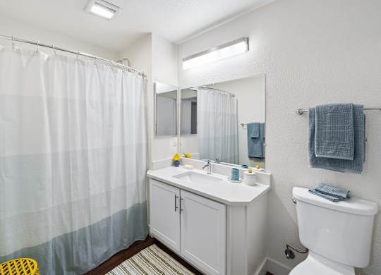 A white bathroom with a white toilet, sink, and shower curtain.