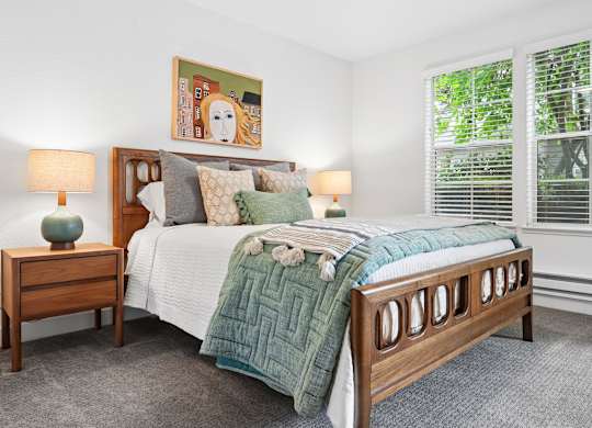 A bedroom with a large bed and a painting on the wall.