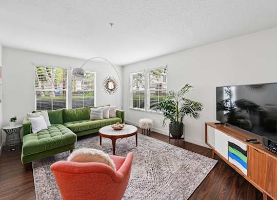 A living room with a green couch, a red chair, and a television.